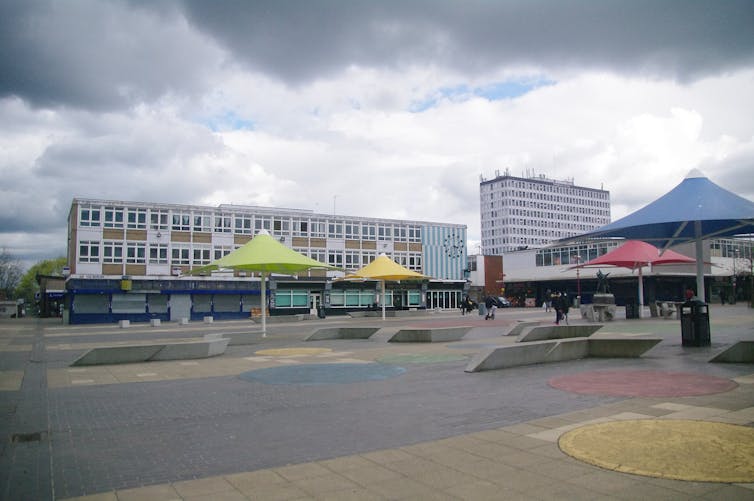 A public square with high rise buildings under a grey class=