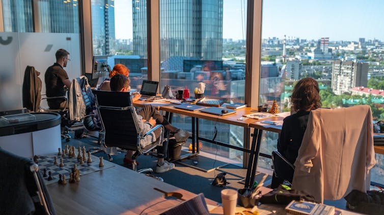 Office workers in front of a wall of windows.