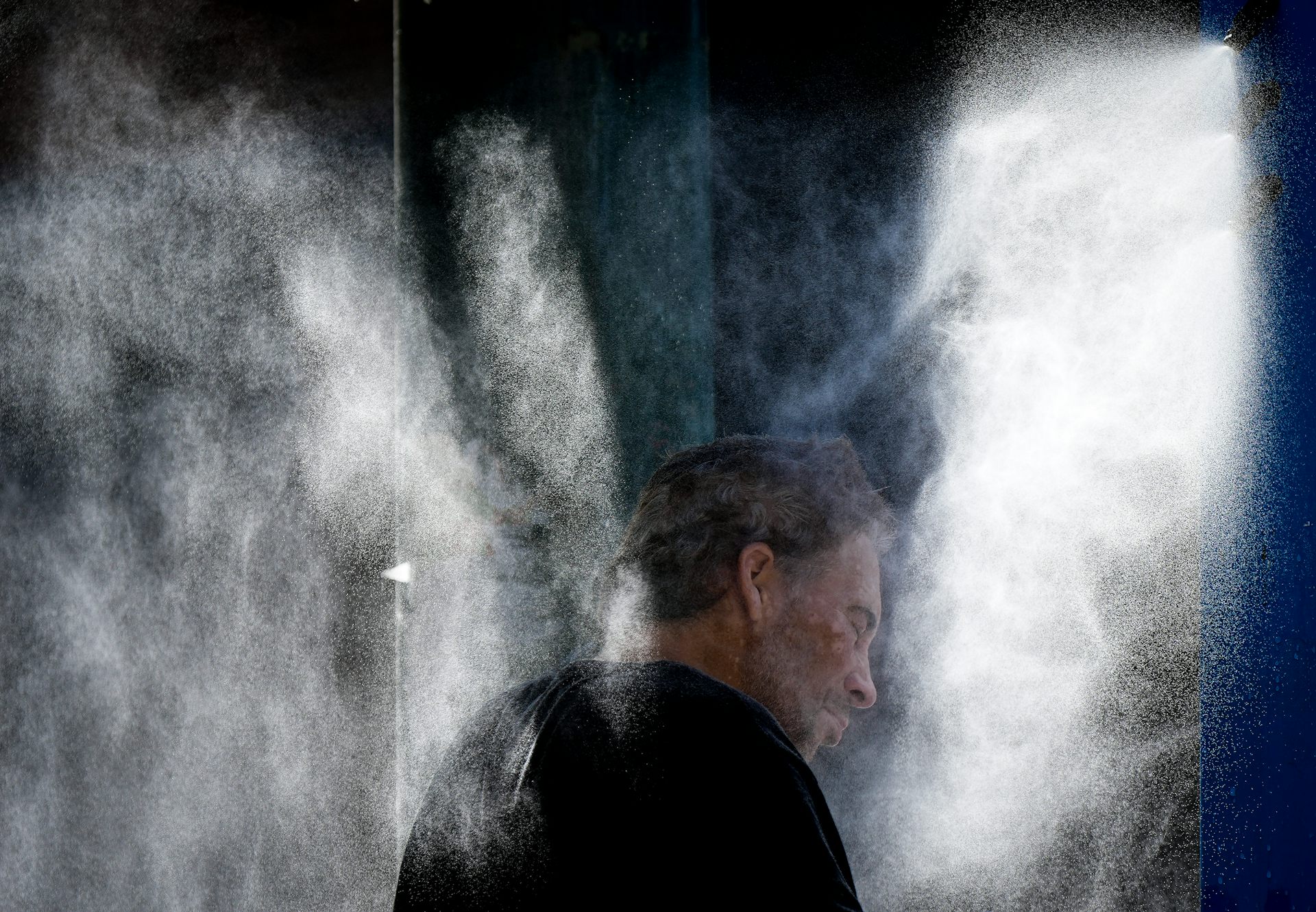 A man stands in a misting station.