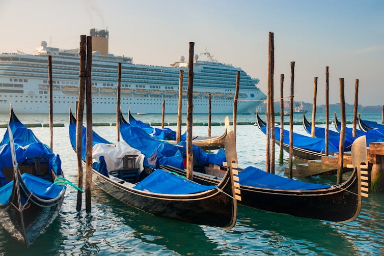 Gondoles au premier plan d’un énorme bateau de croisière à Venise.