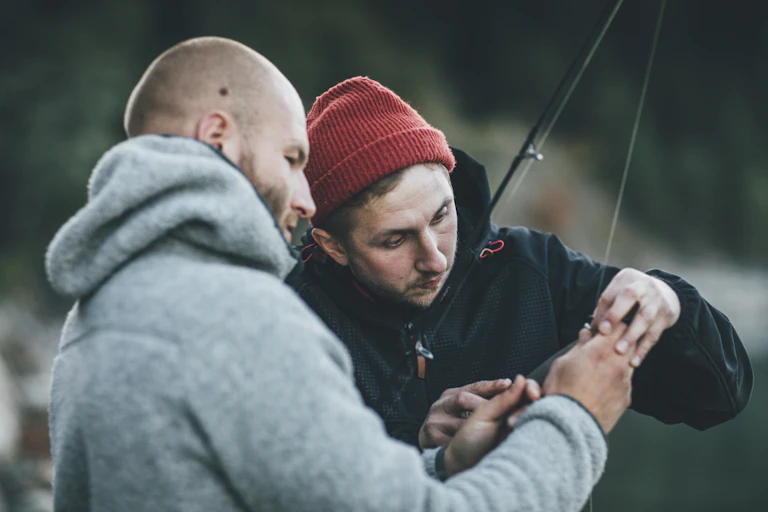 two men handling a fishing hook on a line
