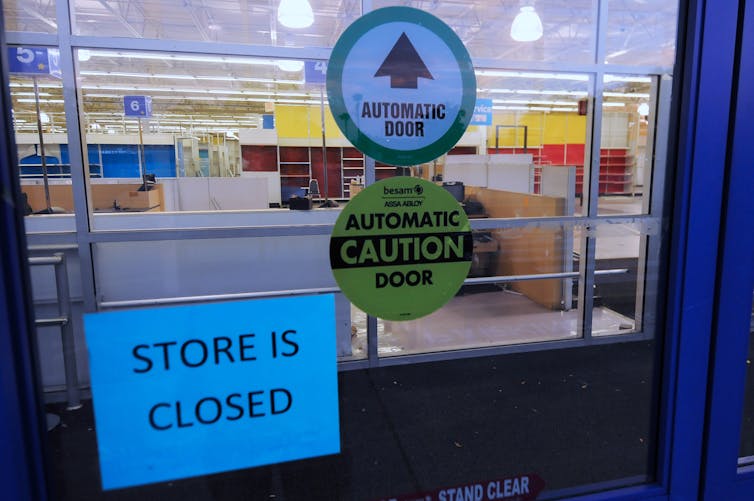 A STORE IS CLOSED sign is affixed to an automatic door at the entrance of a Toys R Us location.