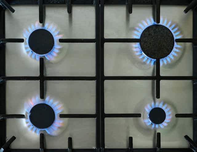 Four gas burners firing on a stovetop