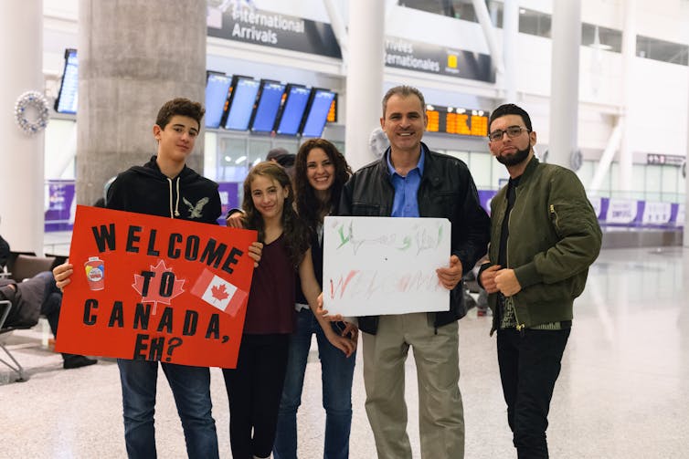 A group of people holding signs that say welcome to Canada
