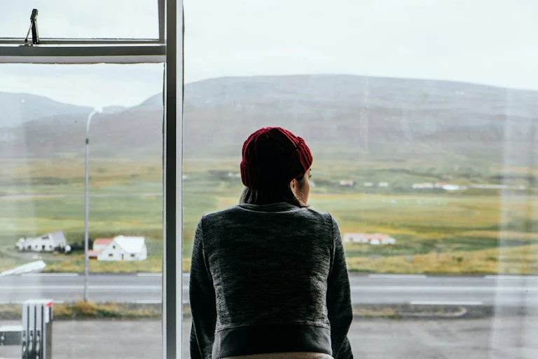Woman looks out window to farmland