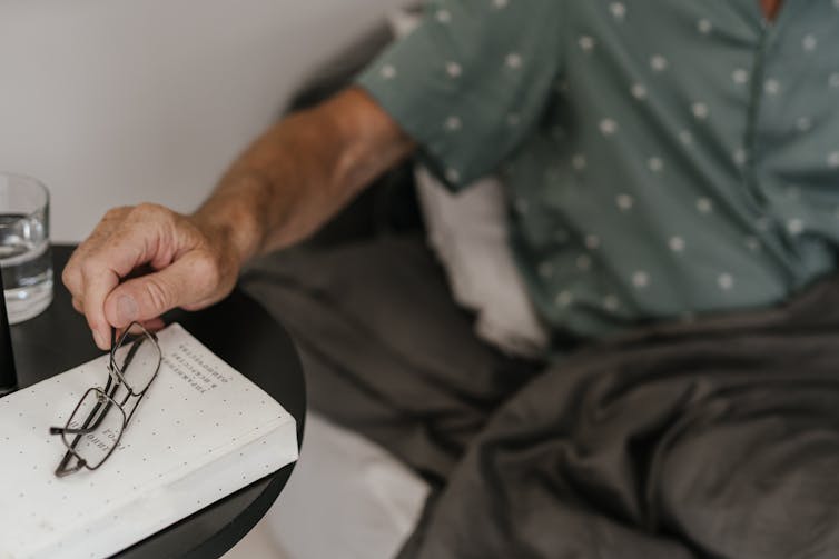 Man reaches for glasses next to his bed