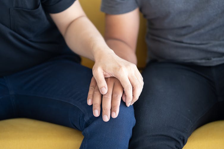 Close up of a person holding another person's hand, on their knee