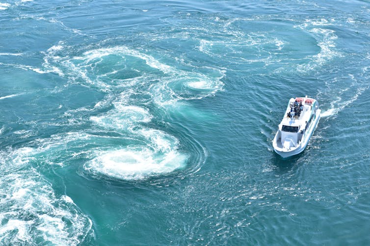 a boat next to a whirlpool in Naruto, Japan