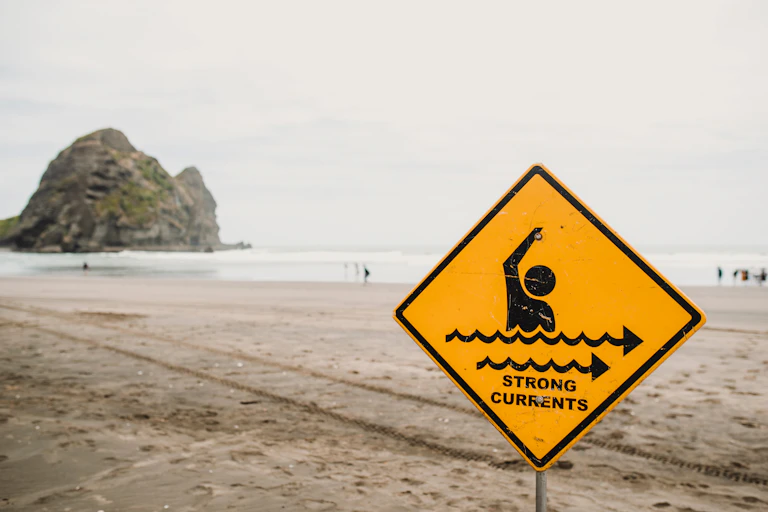 yellow sign showing warning about currents at the beach