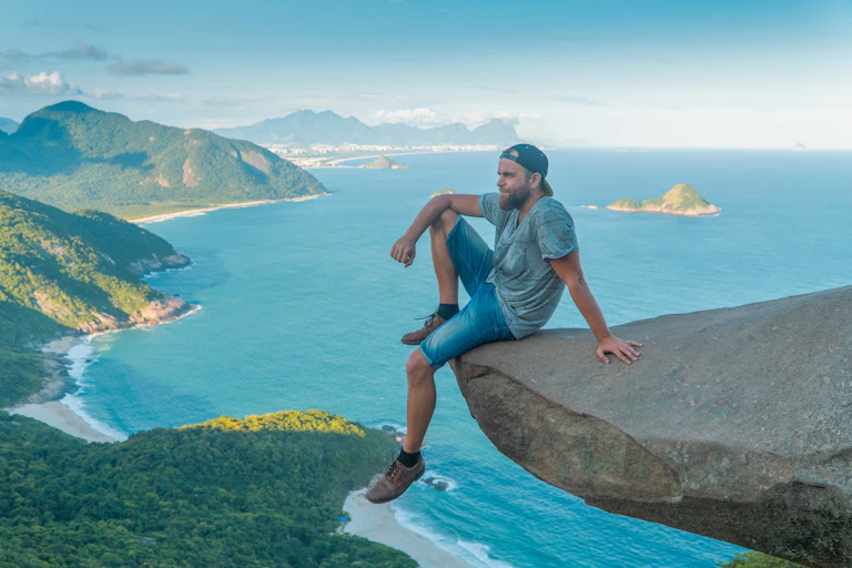 man sitting on risky rock high above sea