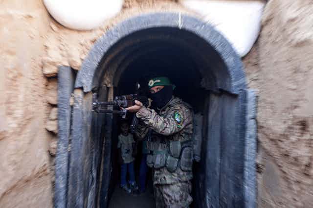 A Hamas fighter in military uniform demonstrates use of one of the group's tunnels.