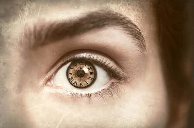 Close up of woman's eye, clock reflection in her pupil