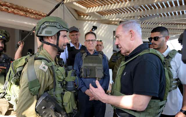 Israeli prime minister Benjamin Netanyahu talks with a soldier as aides stand in the background.