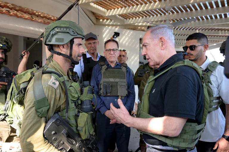 Israeli prime minister Benjamin Netanyahu talks with a soldier as aides stand in the background.