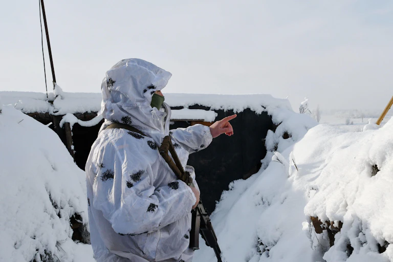 A man in a white suit stands in the snow.