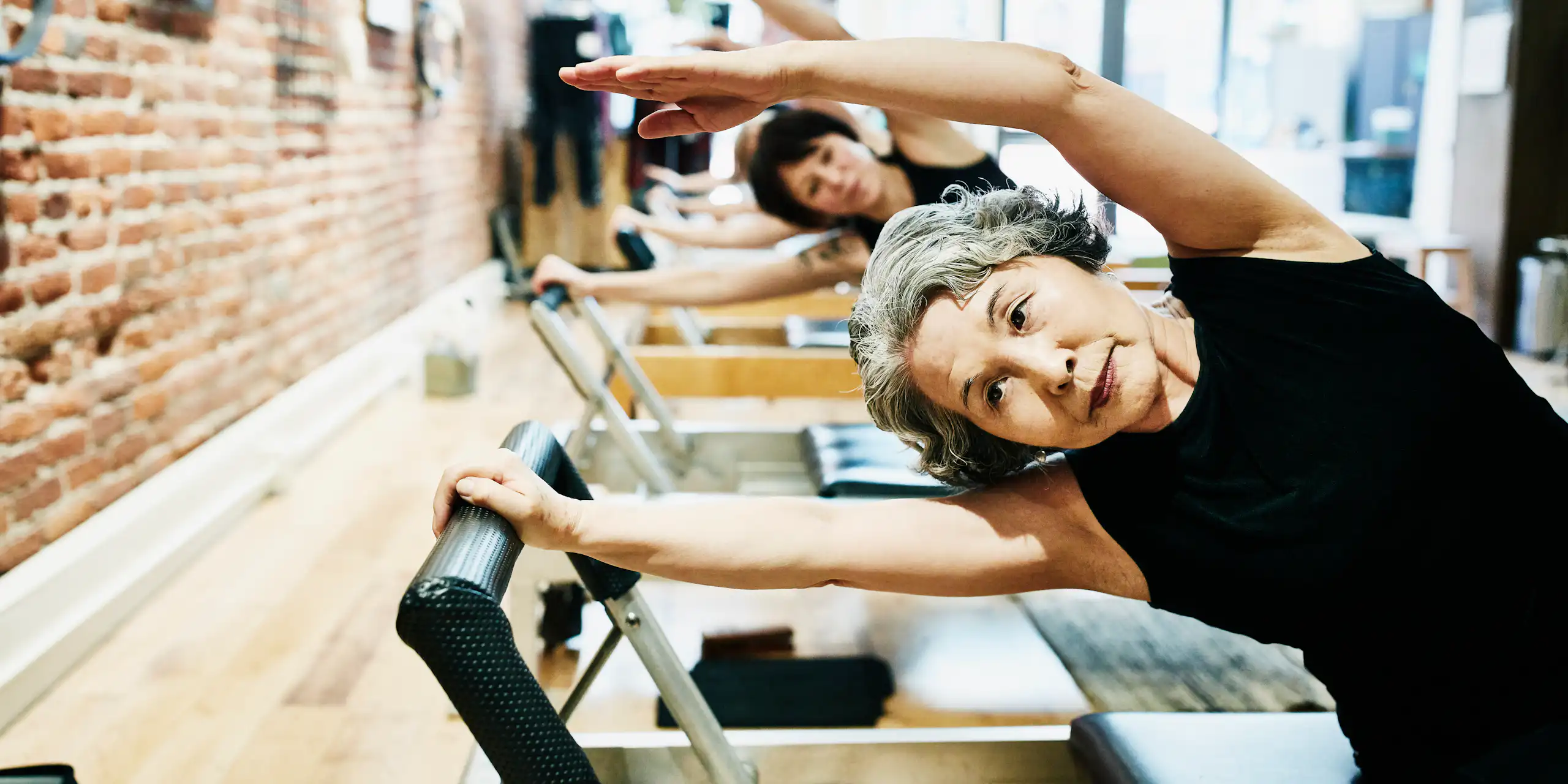 Mujeres maduras haciendo ejercicios en equipos de pilates en un gimnasio.