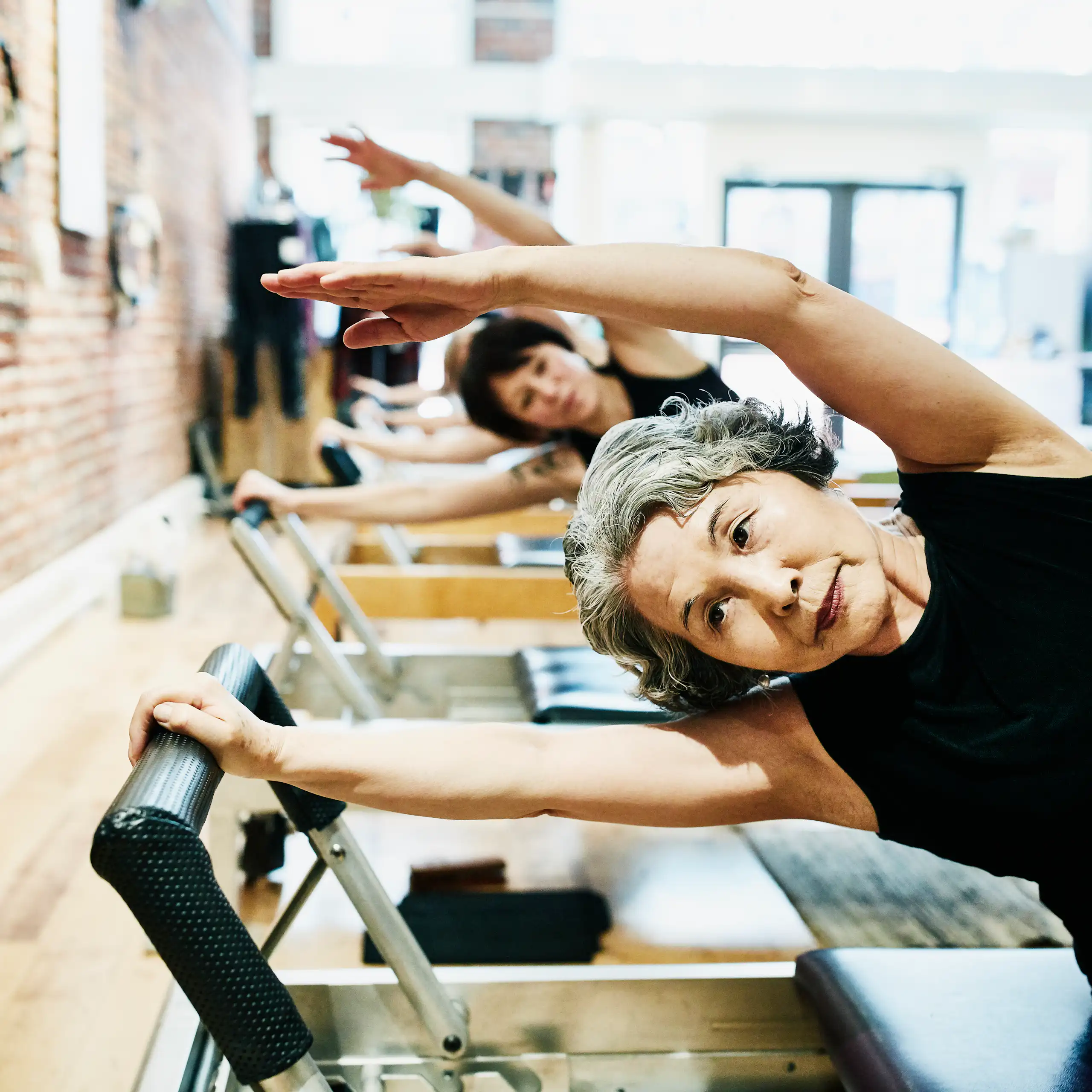 Mujeres maduras haciendo ejercicios en equipos de pilates en un gimnasio.
