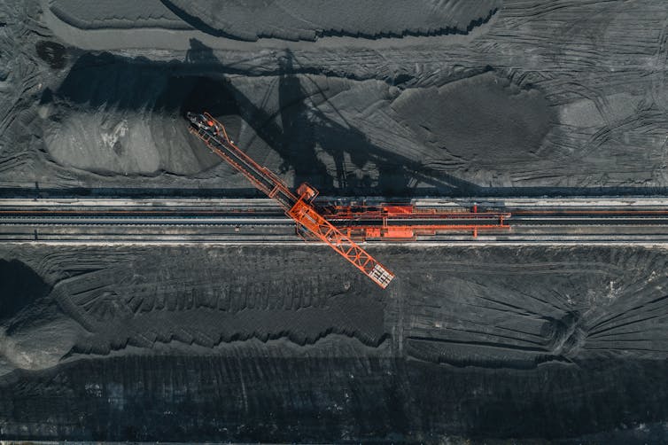 A bird's eye view of a gray rock, with a red crane on it.