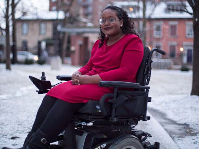 A Black woman wearing a red dress sitting in an electric wheelchair