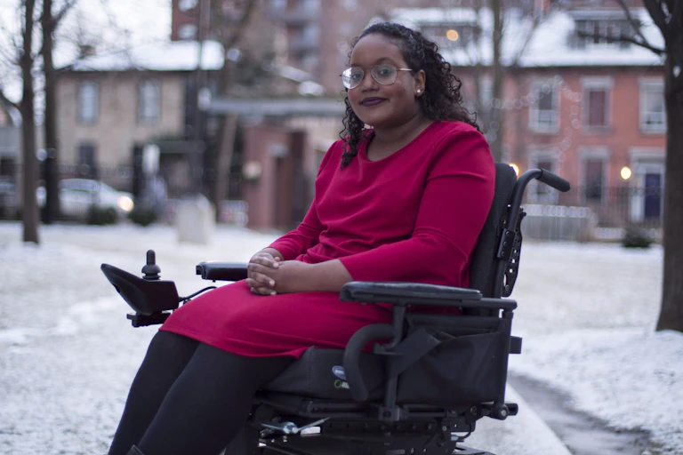 A Black woman wearing a red dress sitting in an electric wheelchair