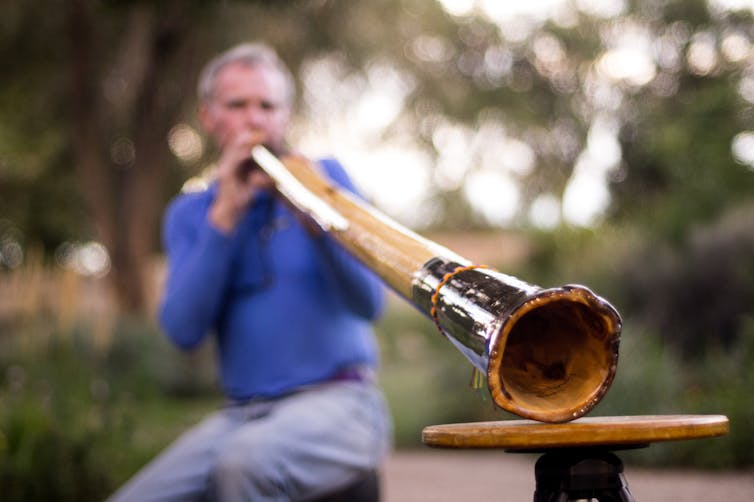 Man playing didgeridoo outside
