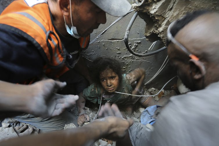Men work to free a young girl from rubble and debris