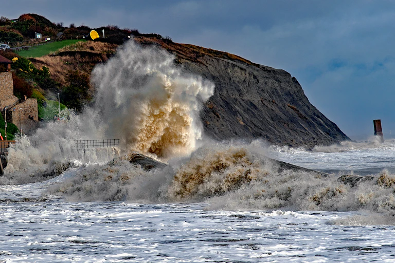 Waves crashing against cliffs during a storm.