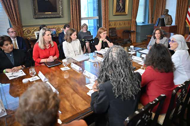 A group of women in business dress sit around a conference table