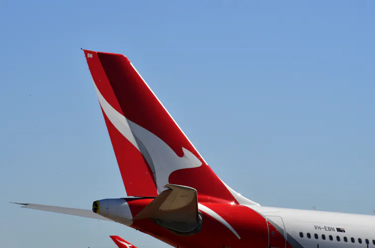 A Qantas plane sits on the tarmac, displaying its distinctive kangaroo symbol on the tail.