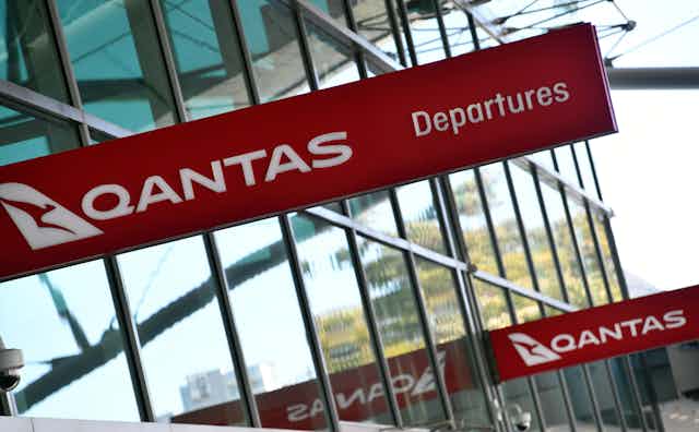 A Qantas sign is displayed at an airport.