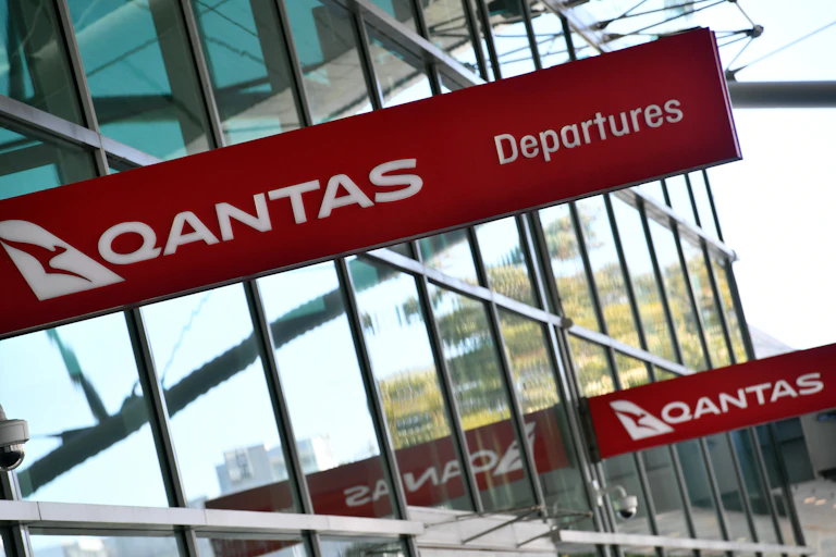 A Qantas sign is displayed at an airport.
