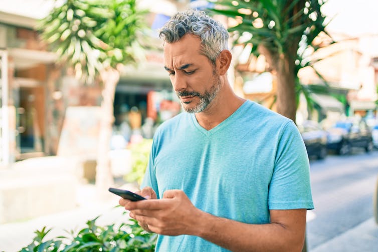 A man outdoors on his smartphone.