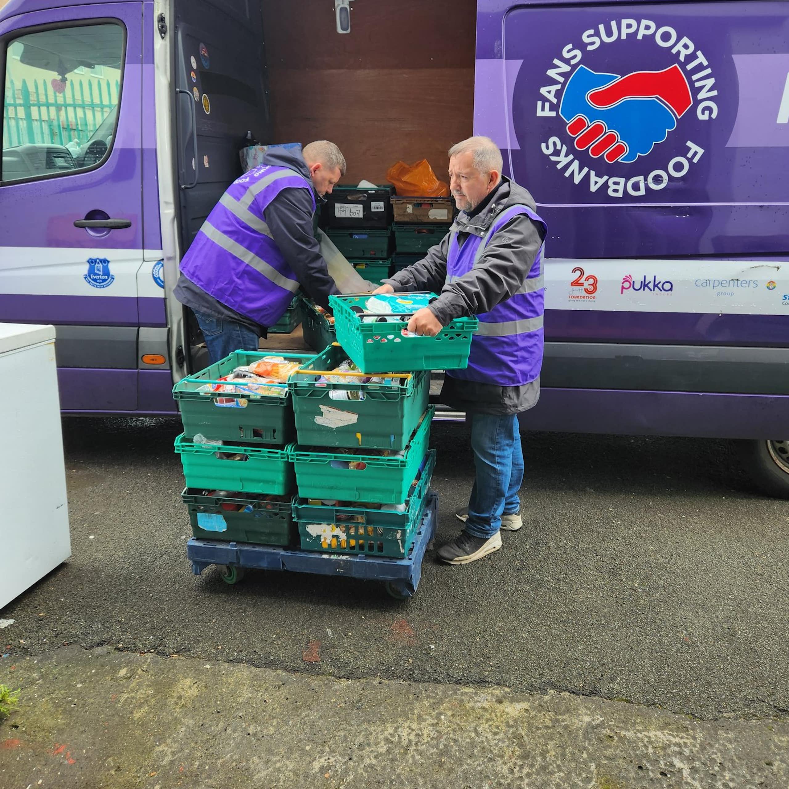 Two men loading crates of food into a fan.