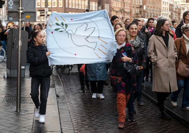 Peace march in Amsterdam -- two women carry a banner with the dove of peace.