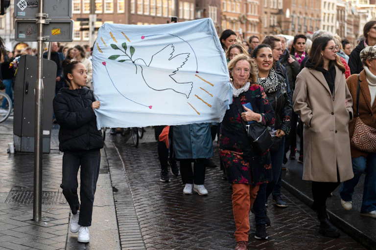 Peace march in Amsterdam -- two women carry a banner with the dove of peace.