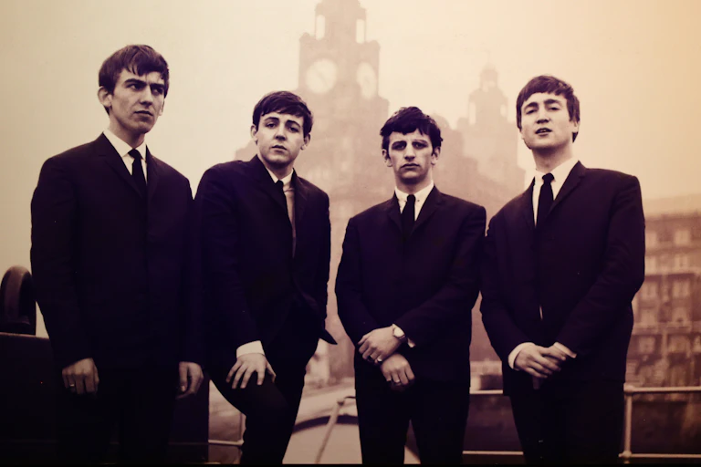 A black and white image of the Beatles in the early 1960s dressed in black suits.