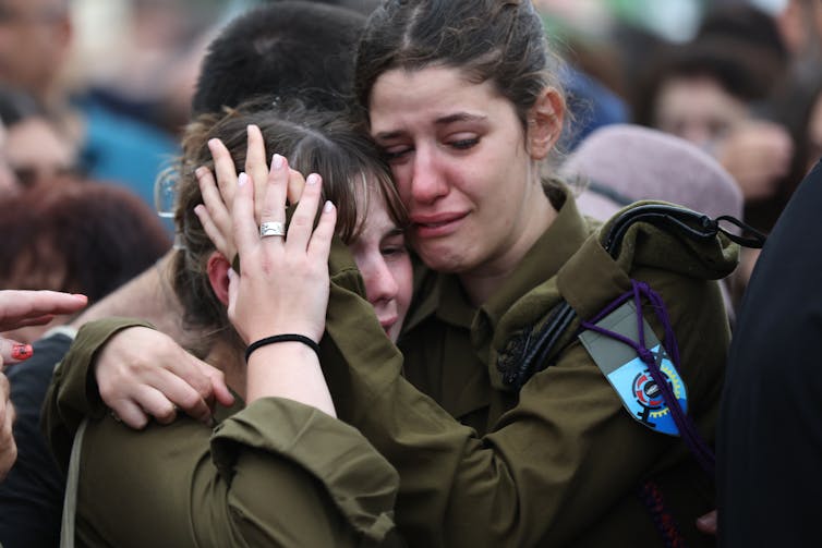 Women in army uniforms hold each other at the funeral of a comrade from the Israel Defence Forces, October 2023.