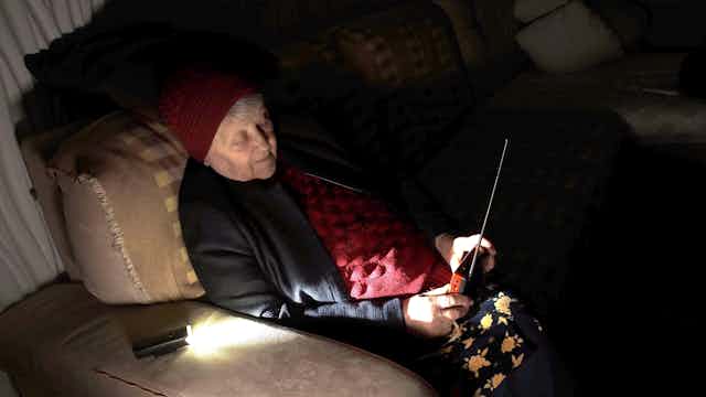 A woman sitting in the dark listening to the radio.