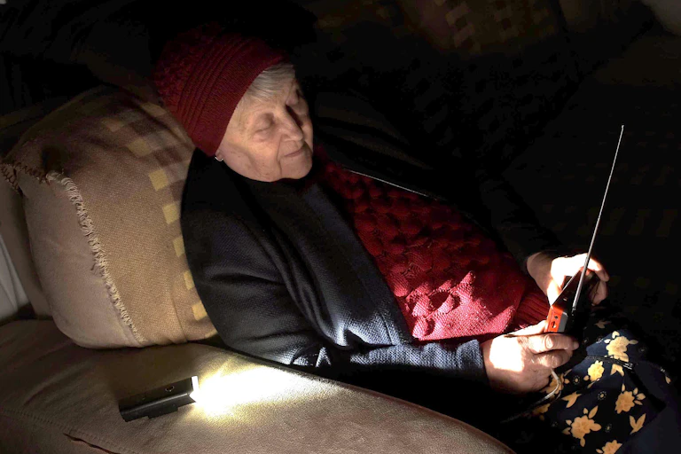 A woman sitting in the dark listening to the radio.