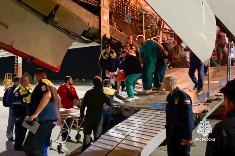 A group of men search and aircraft on the runway in a Dagestan airport as officials look on.