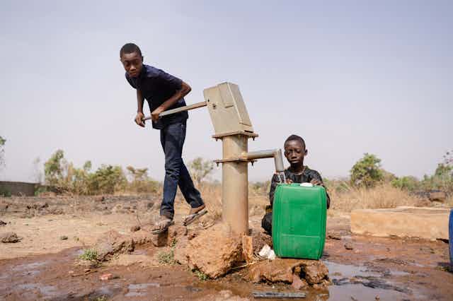 Two boys at a water pump