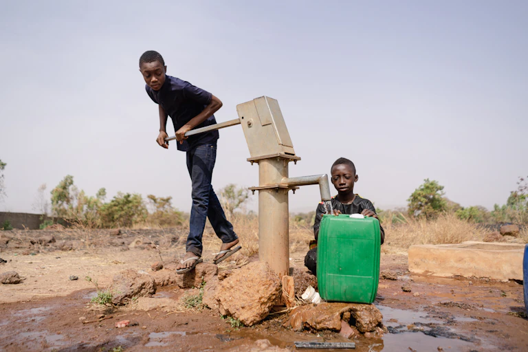 Two boys at a water pump