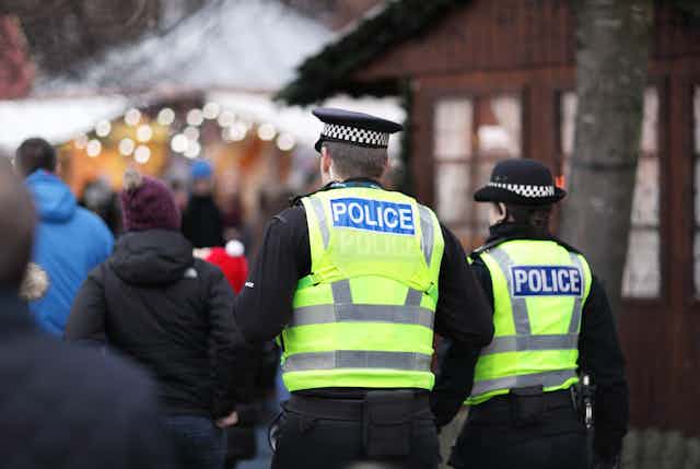 View from behind of two police officers walking through a busy Christmas market