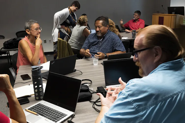 People seen in front of computers in discussion.