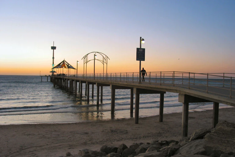 A man walking down a jetty at sunset.