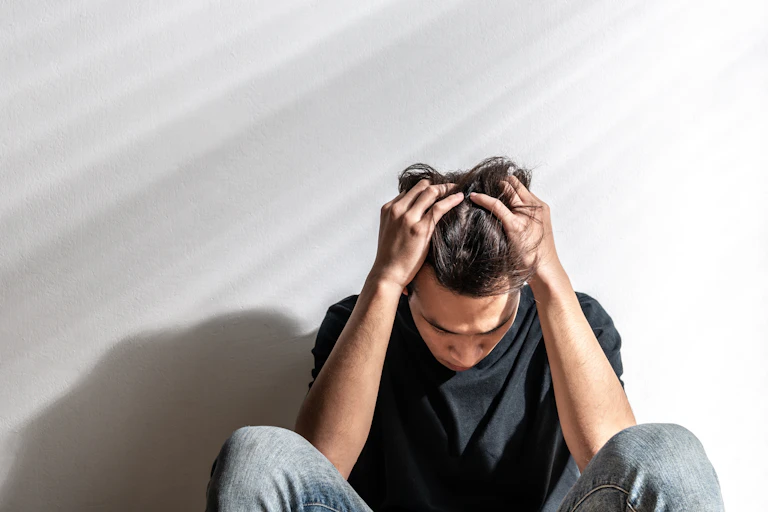 Stressed man sitting on the floor holding head in his hands