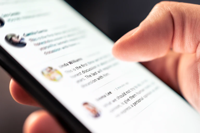 Hand holding phone showing social media posts