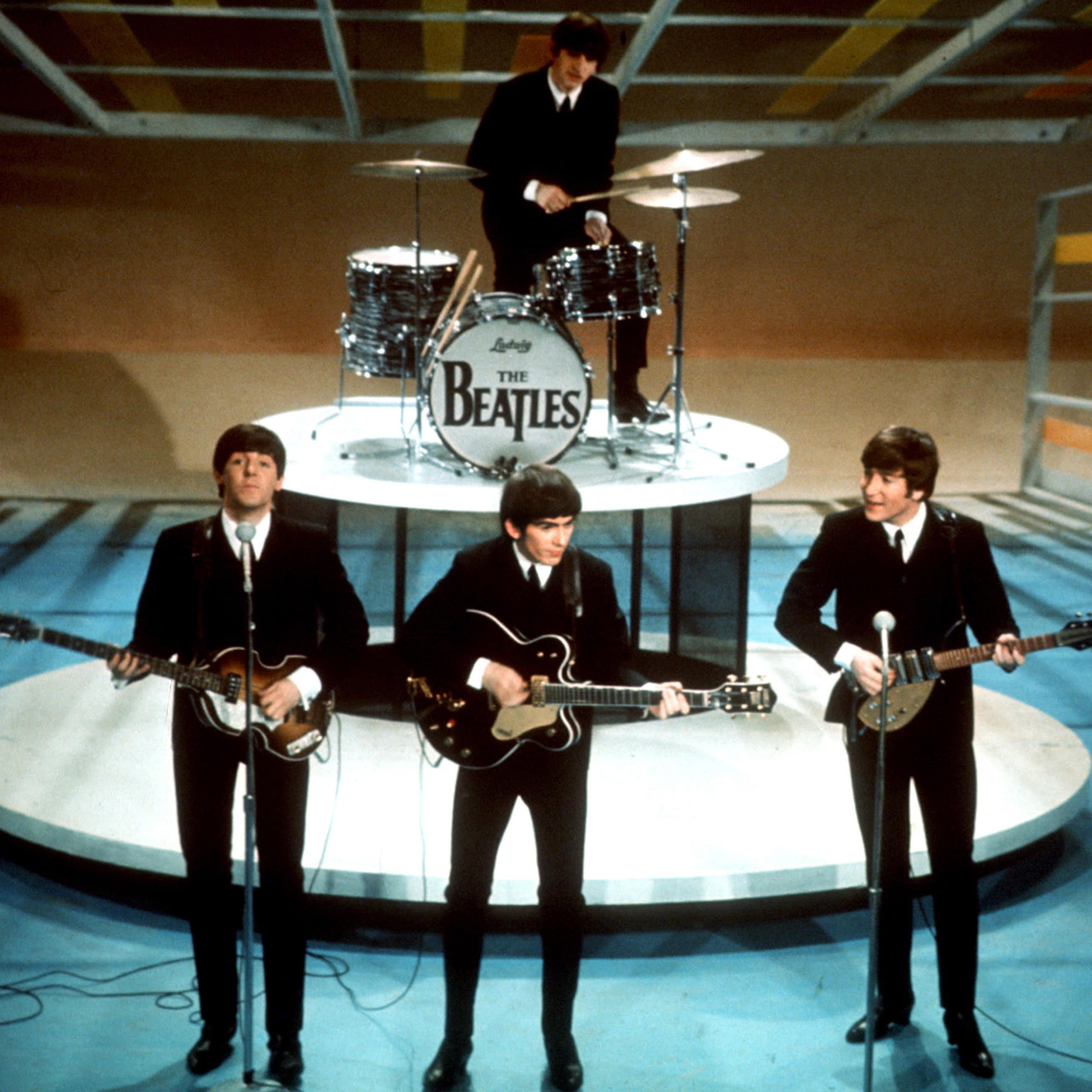 Les Beatles sur scène dans les années 60 en costumes noirs
