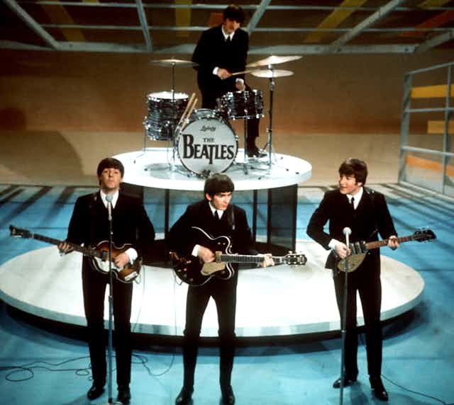 Les Beatles sur scène dans les années 60 en costumes noirs