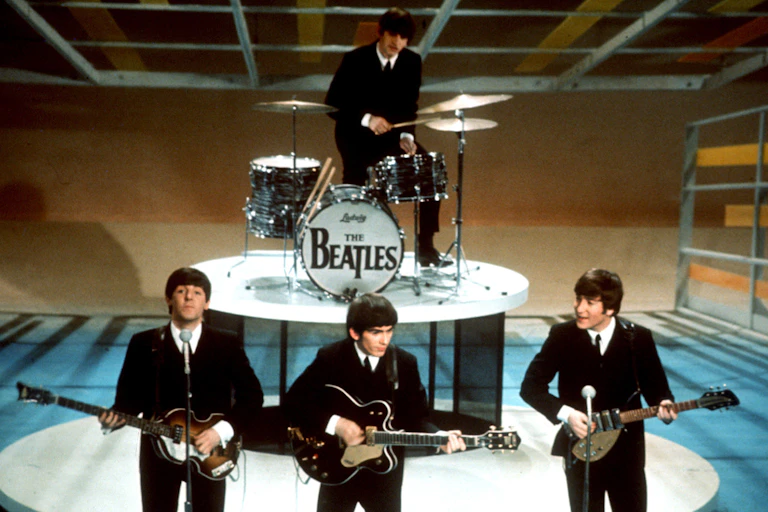 Les Beatles sur scène dans les années 60 en costumes noirs